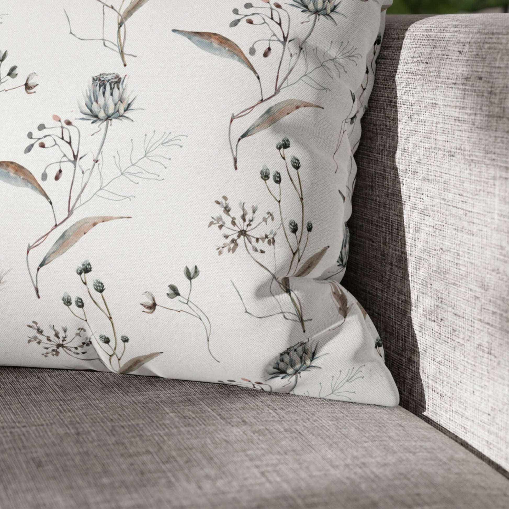 Winter botanical christmas pillow featuring delicate watercolor florals and winter greenery on a cozy couch.