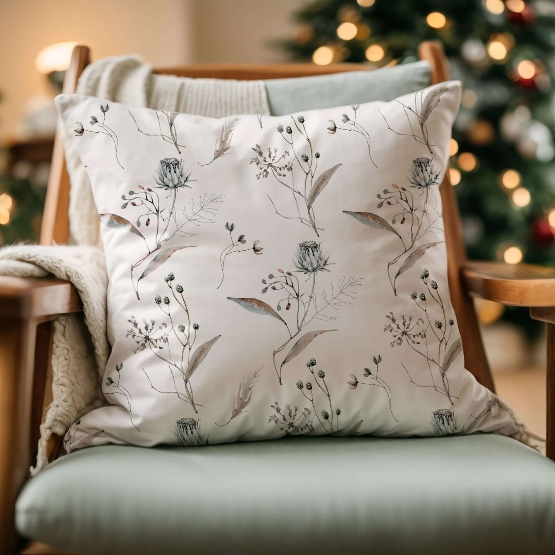Winter botanical christmas pillow with watercolor floral design on cozy chair in festive living room.