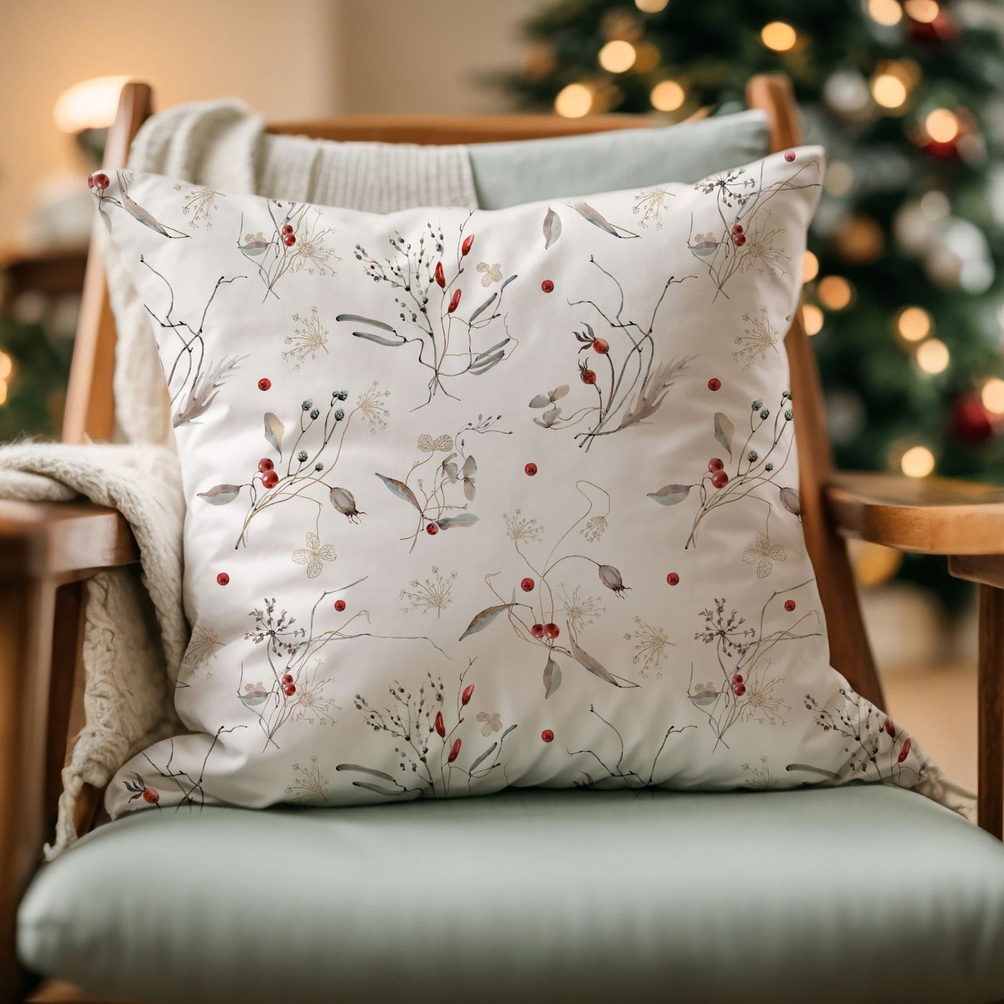 Winter botanical pillow with red berry pattern on chair near Christmas tree