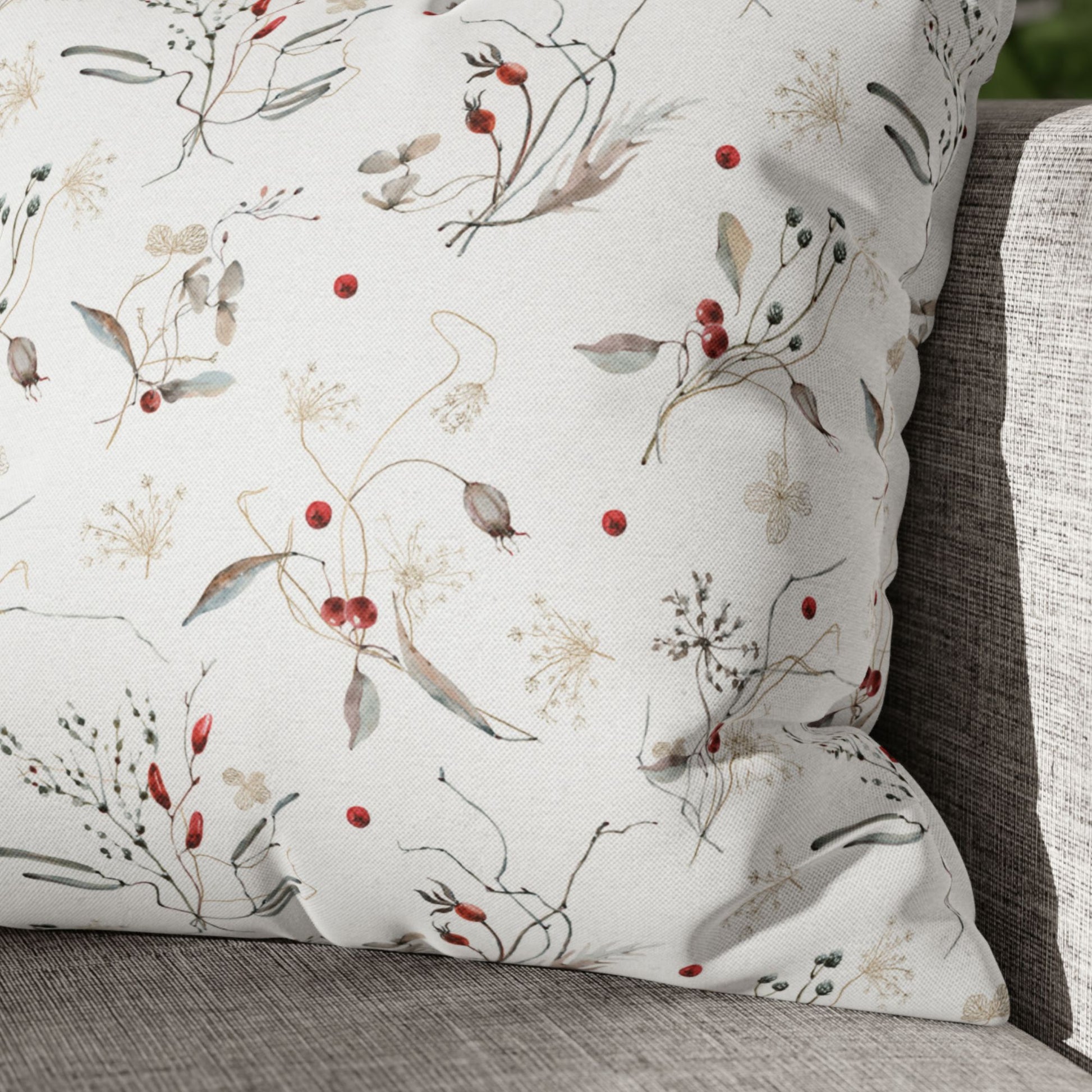 Winter botanical pillow with red berries and delicate foliage on neutral sofa