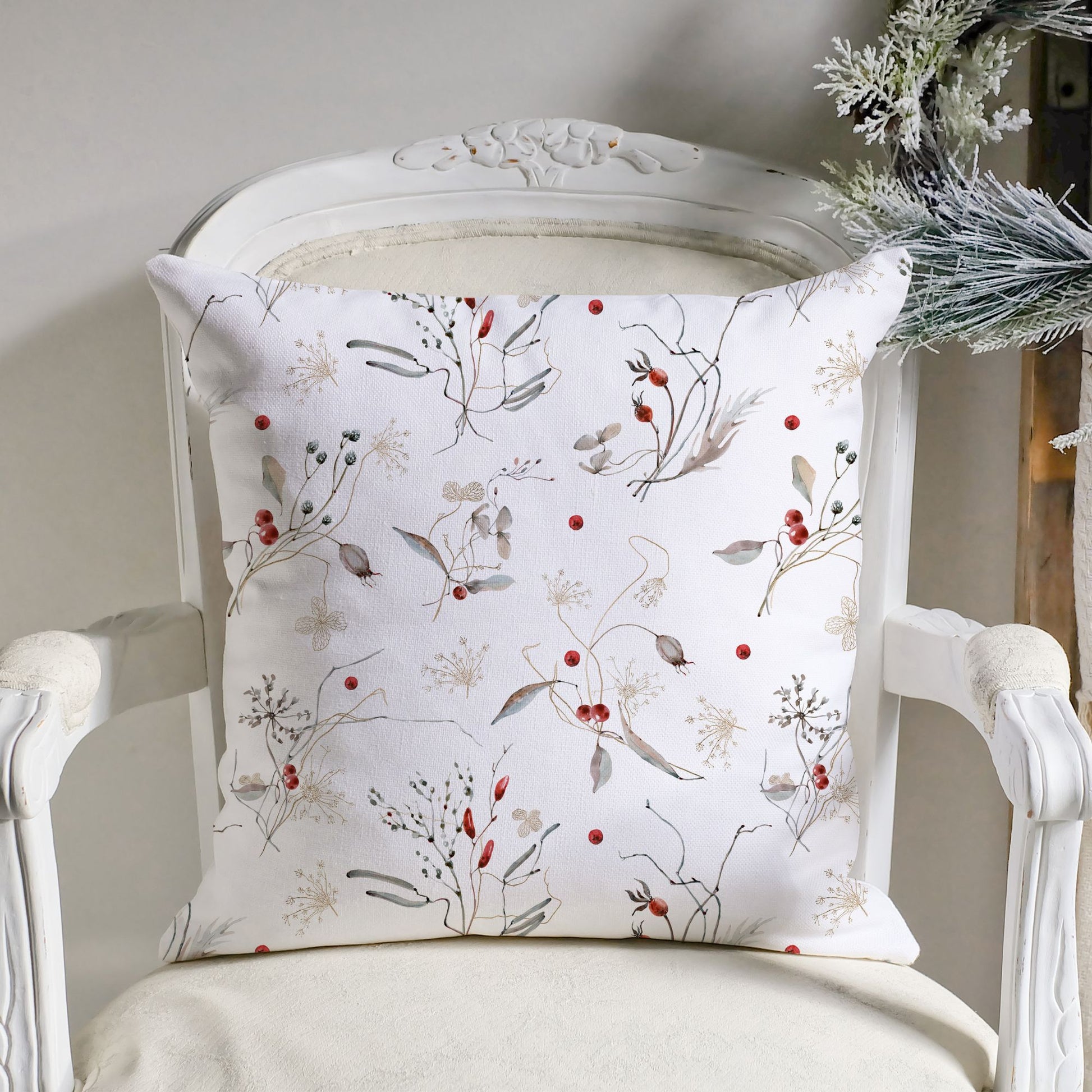 Winter botanical pillow with watercolor red berries and branches on a vintage white chair – nature-inspired seasonal home decor