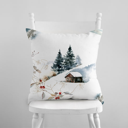 Watercolor winter landscape pillow with snowy cabin and pine trees – cozy seasonal decor