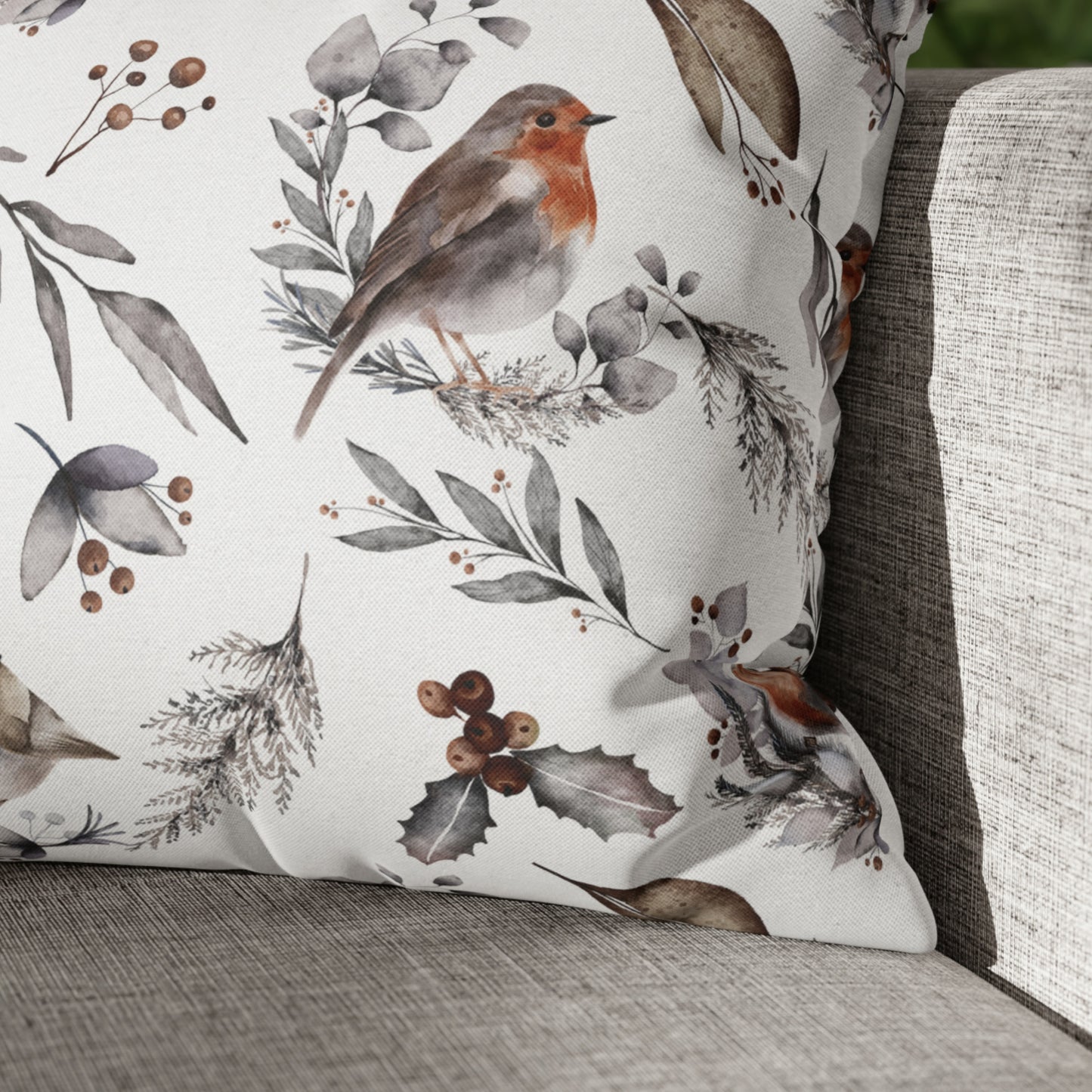 Winter botanical pillow with watercolor robin bird and foliage on neutral linen sofa