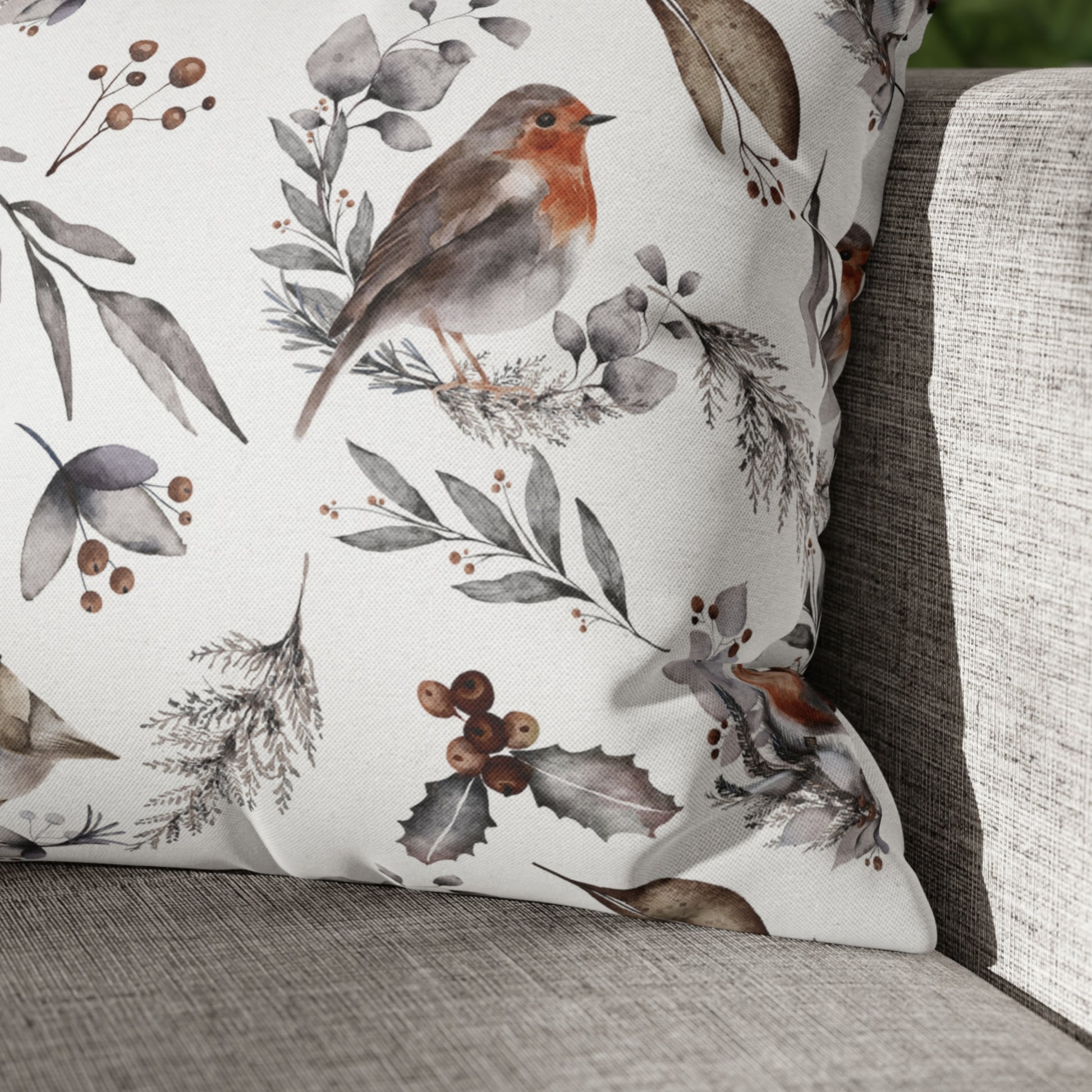 Winter botanical pillow with watercolor robin bird and foliage on neutral linen sofa