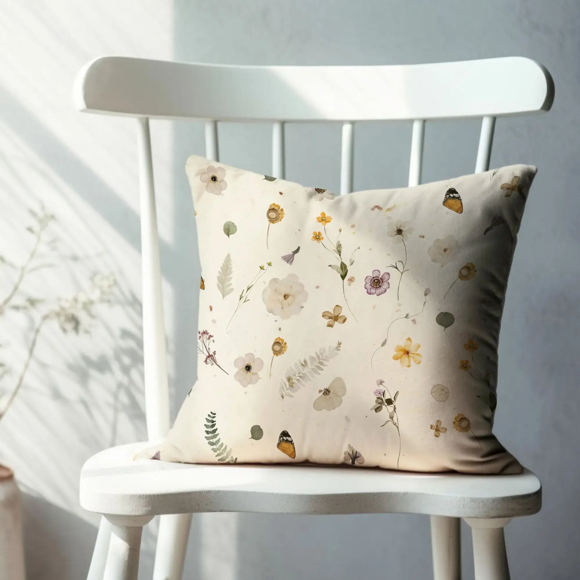 Yellow Watercolor Pressed Flowers PILLOW placed on a white chair with delicate floral designs.