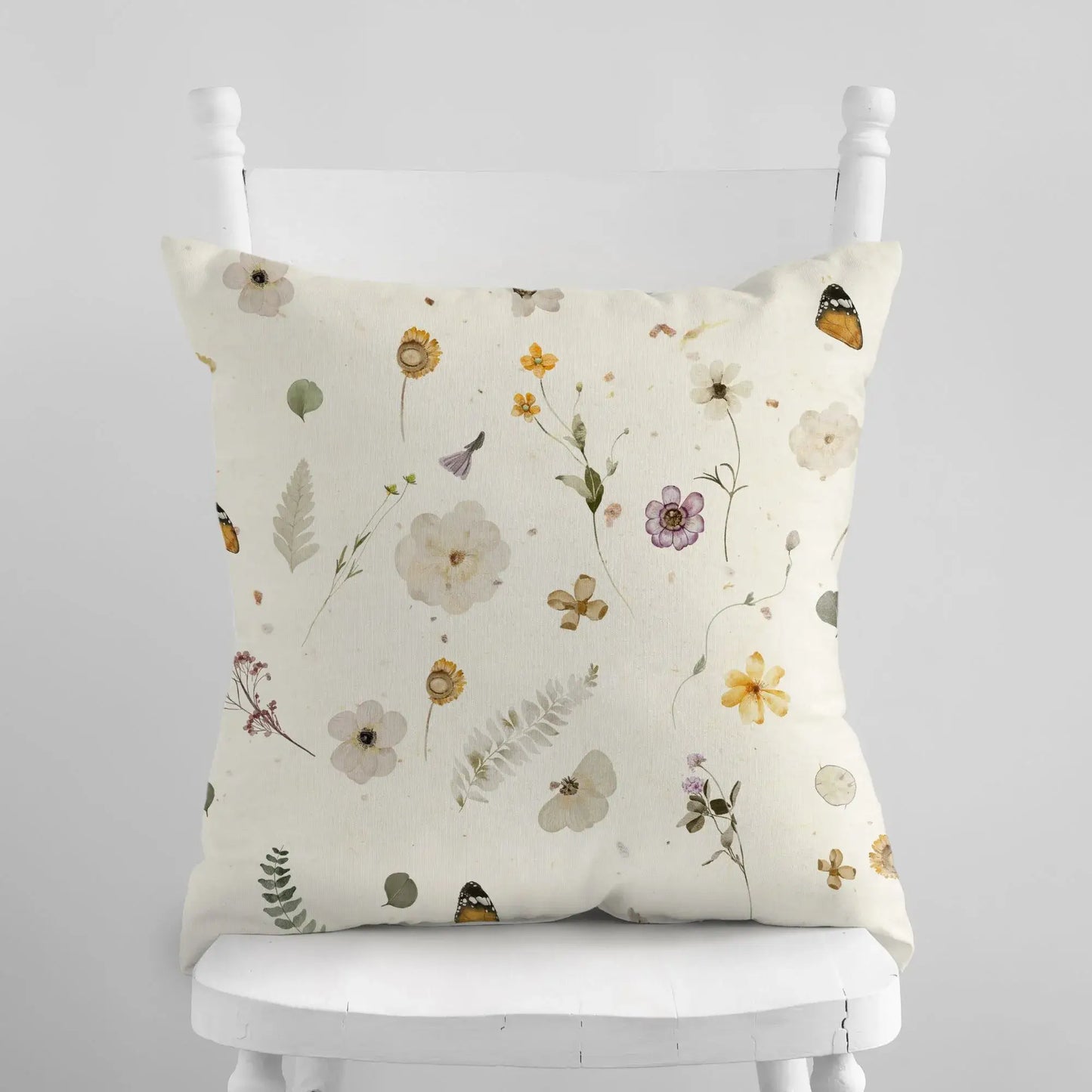 Yellow Watercolor Pressed Flowers PILLOW on a chair with botanical floral design.