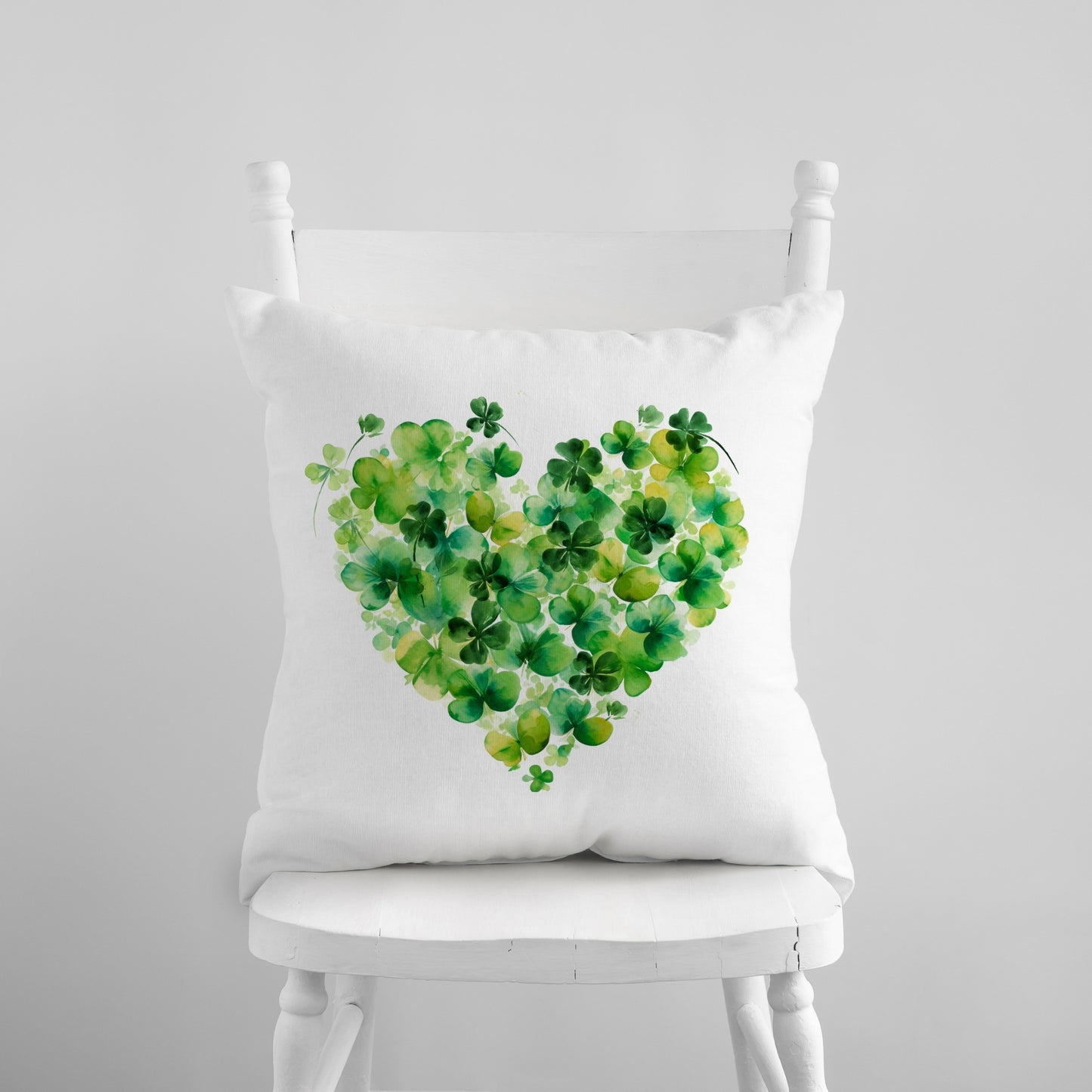 a white chair with a green heart pillow on it