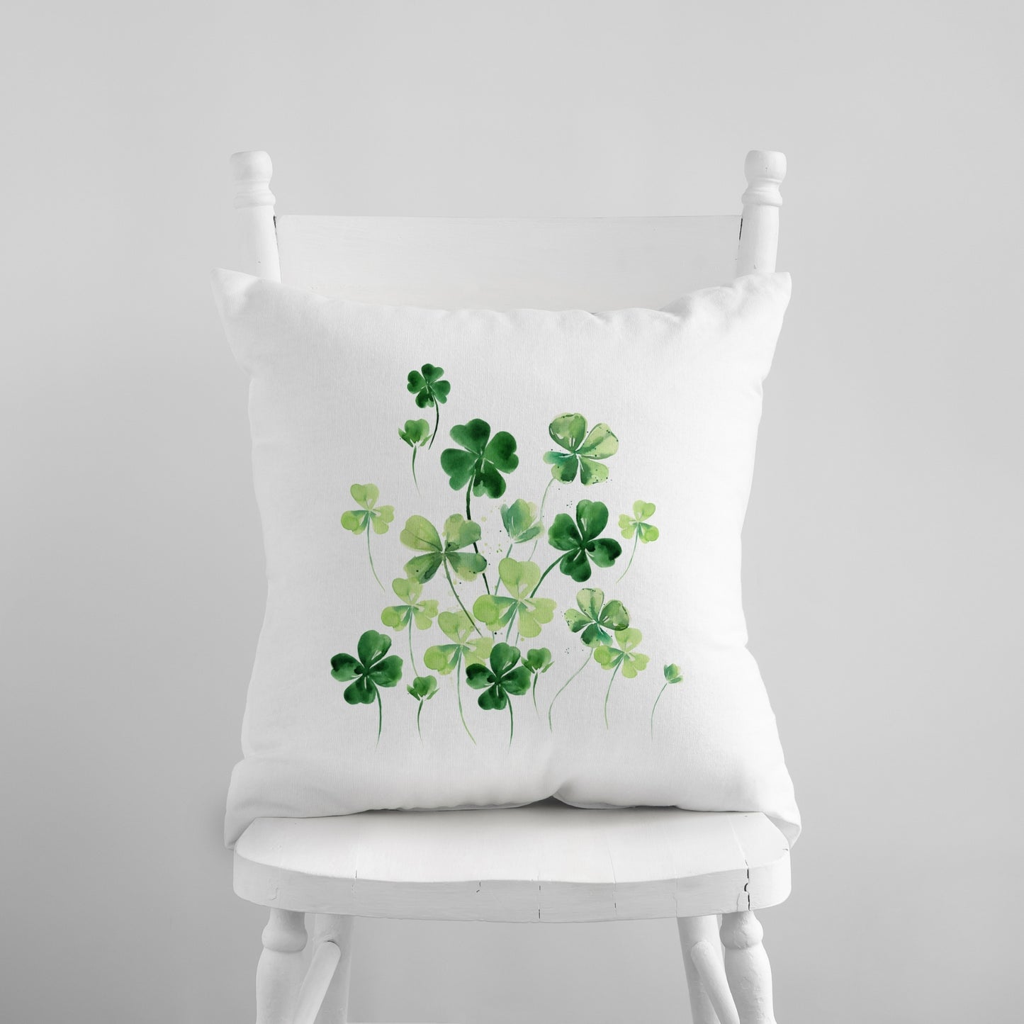 a white chair with a white pillow with green shamrocks on it