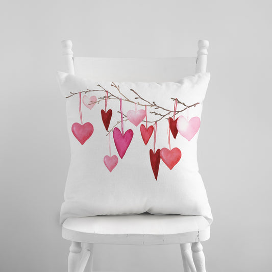 a white chair with a pink and red heart pillow on it