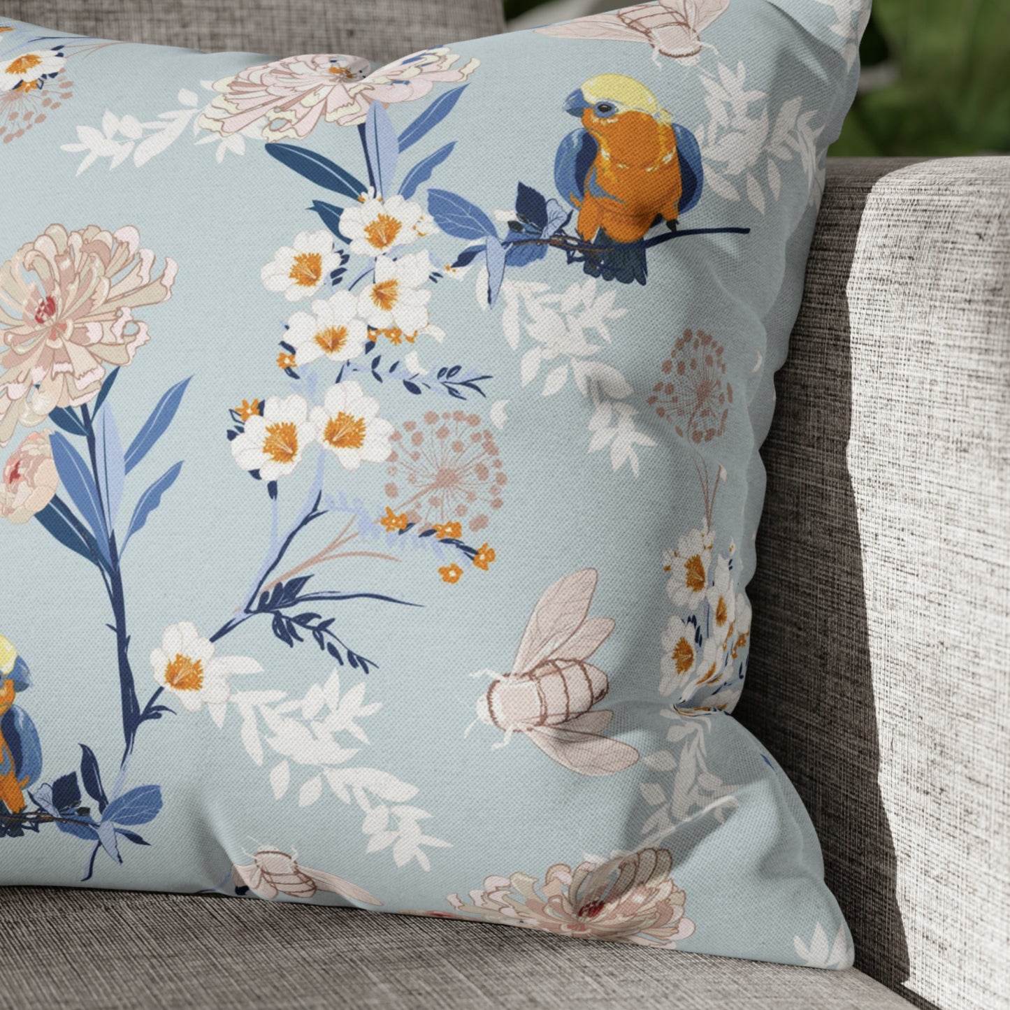 a blue floral pillow on a gray couch