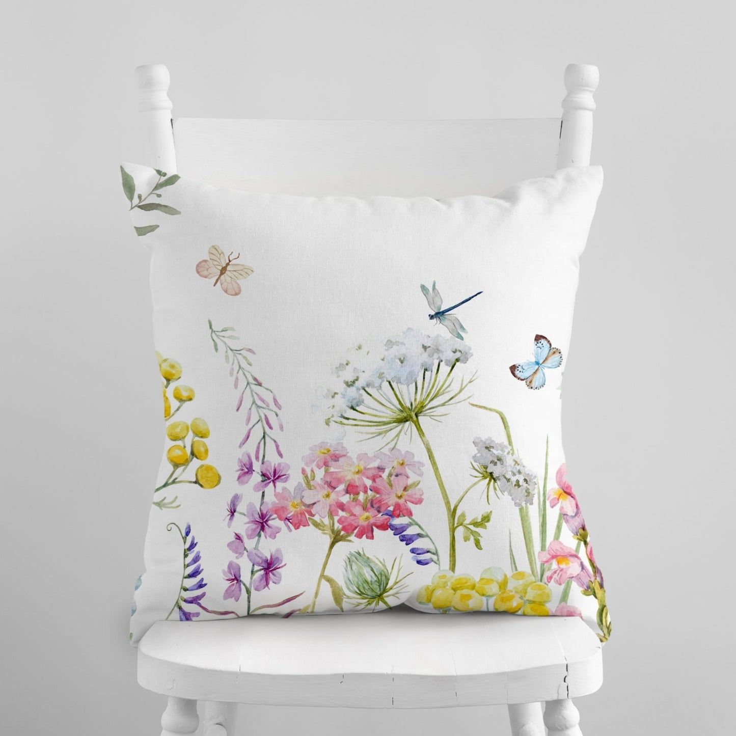 a white chair with a floral pillow on it
