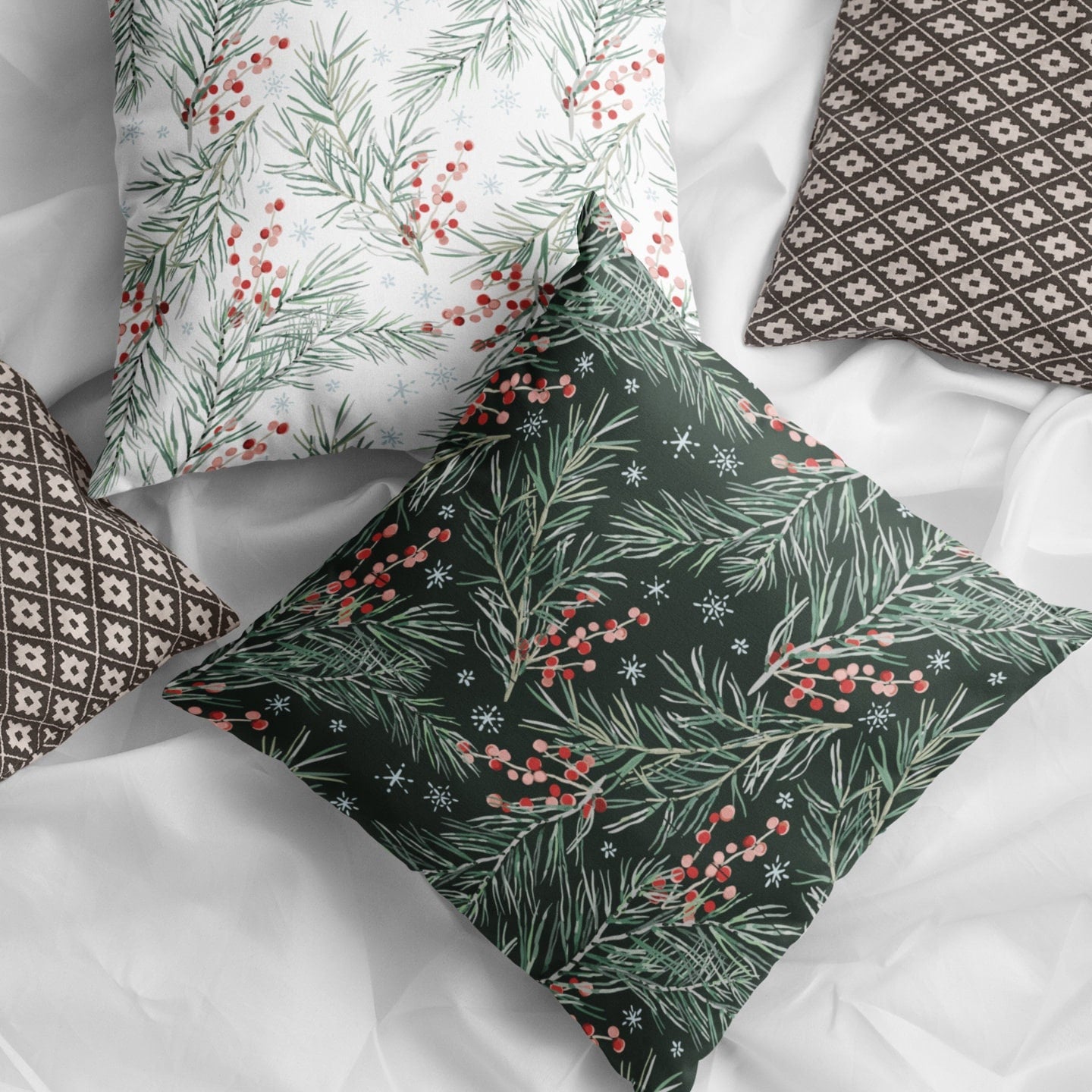 Flat lay of black and white Christmas pillows with pine branches and red berries