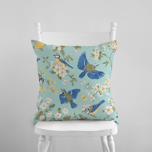 a blue pillow with birds and flowers on it