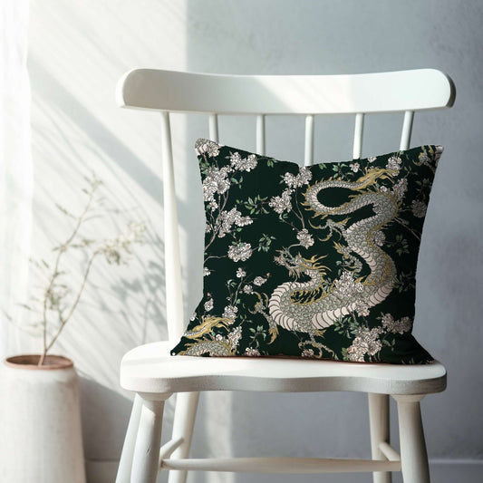 Dark green chinoiserie pillow with dragon and floral design. Oriental decorative pillow on white chair.
