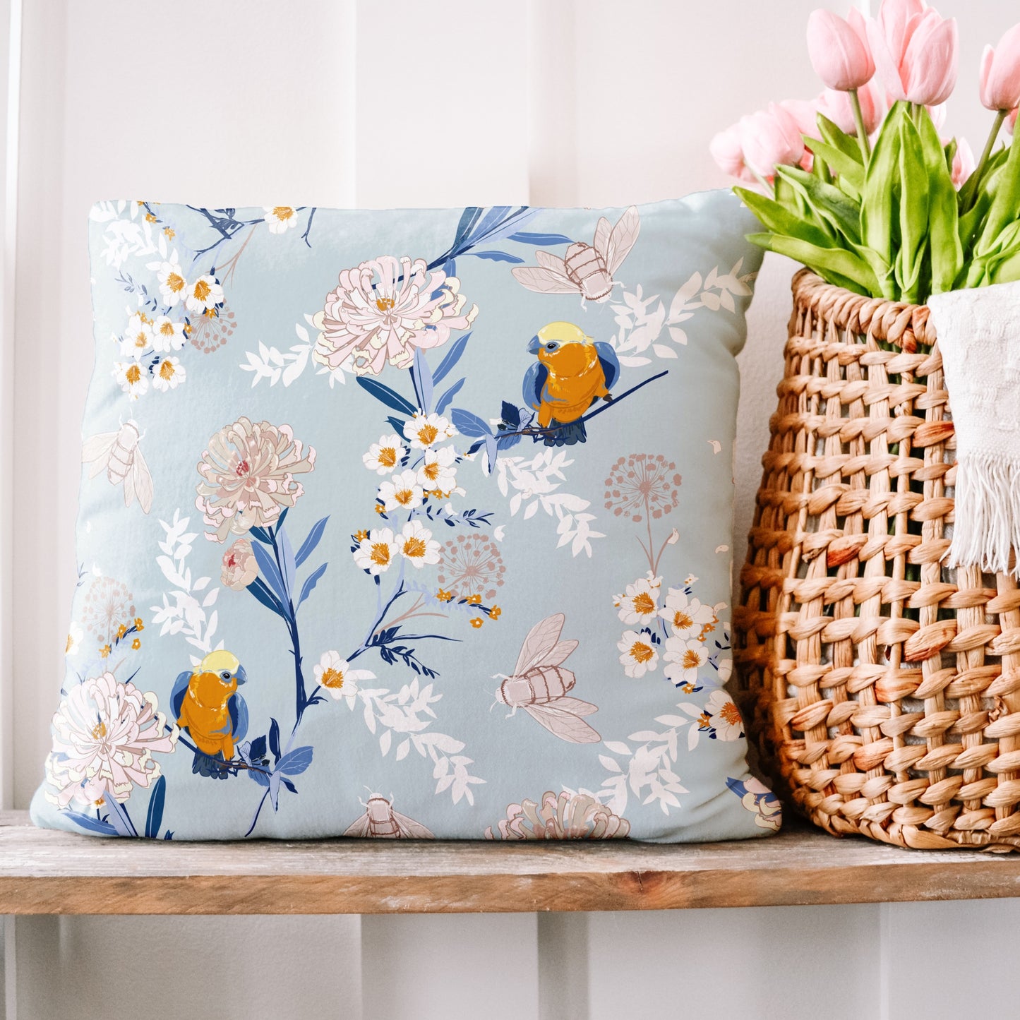 a basket of flowers next to a pillow on a shelf