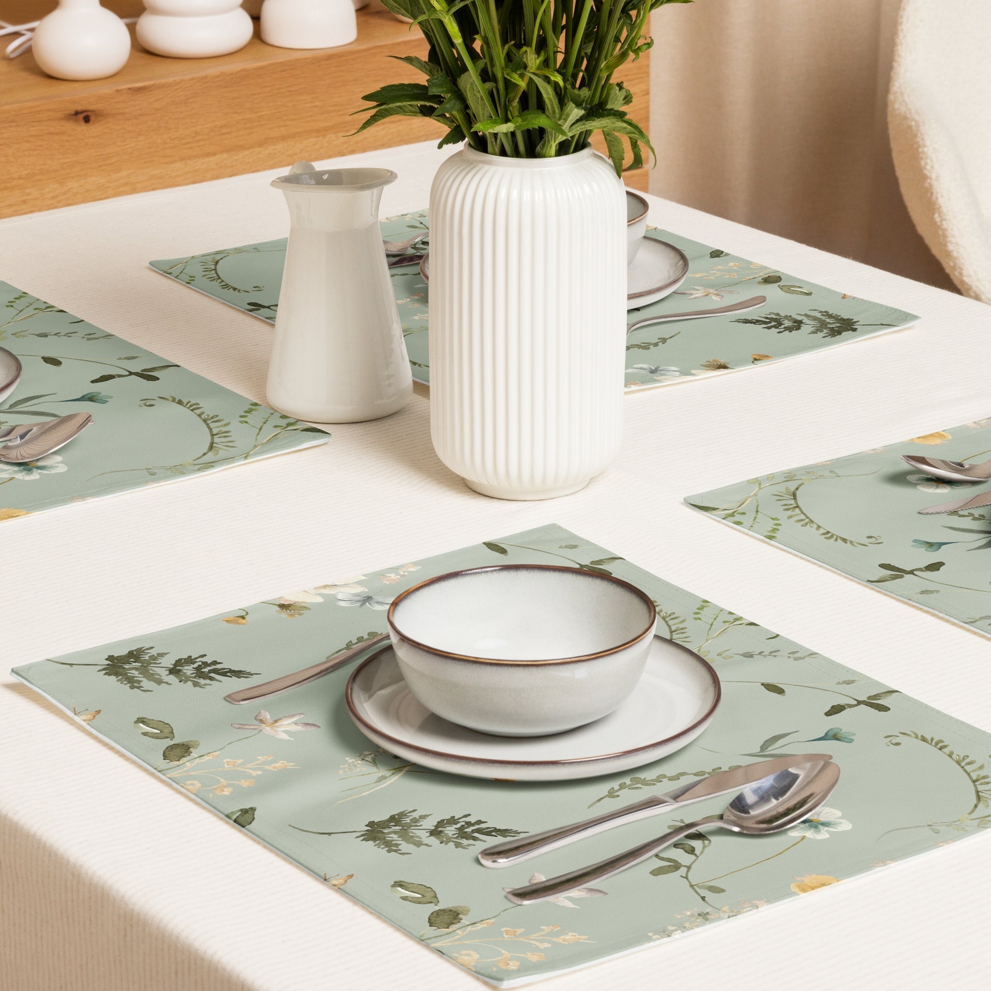 a table with green placemats and a vase with flowers