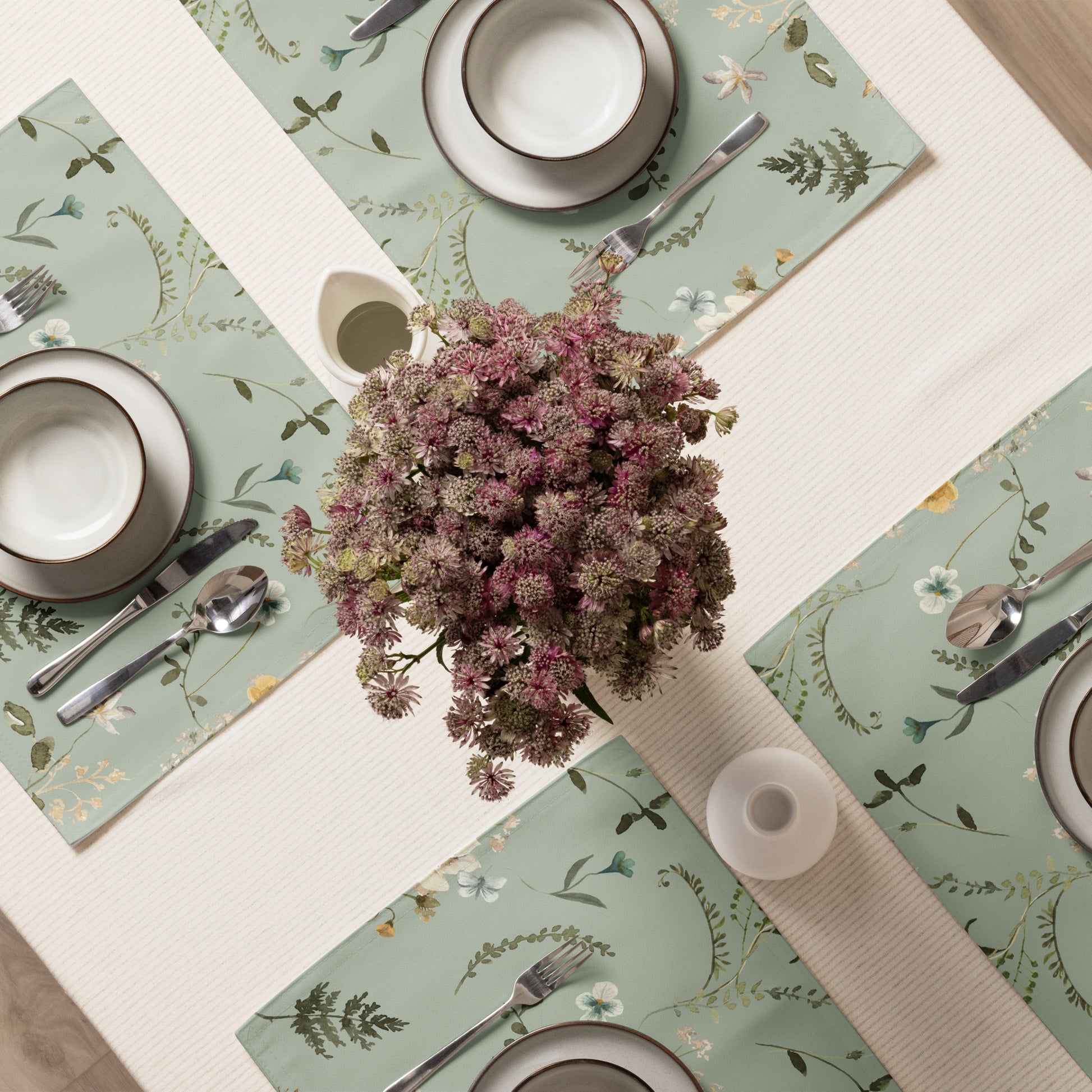 a table with a vase of flowers and Green botanical placemats from Blue Water Songs on top of it