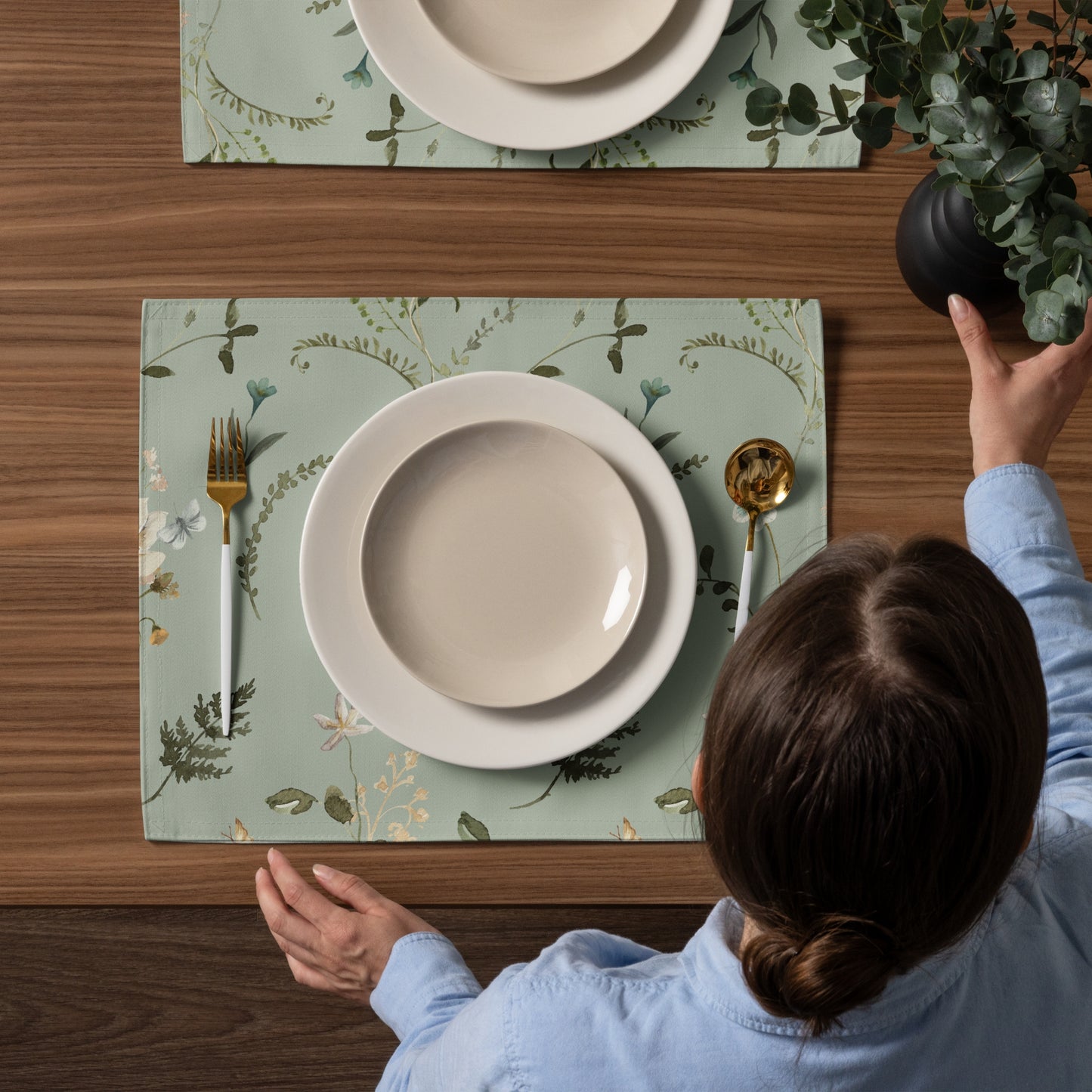 a woman sitting at a table with Green botanical placemat from Blue Water Songs plates and utensils