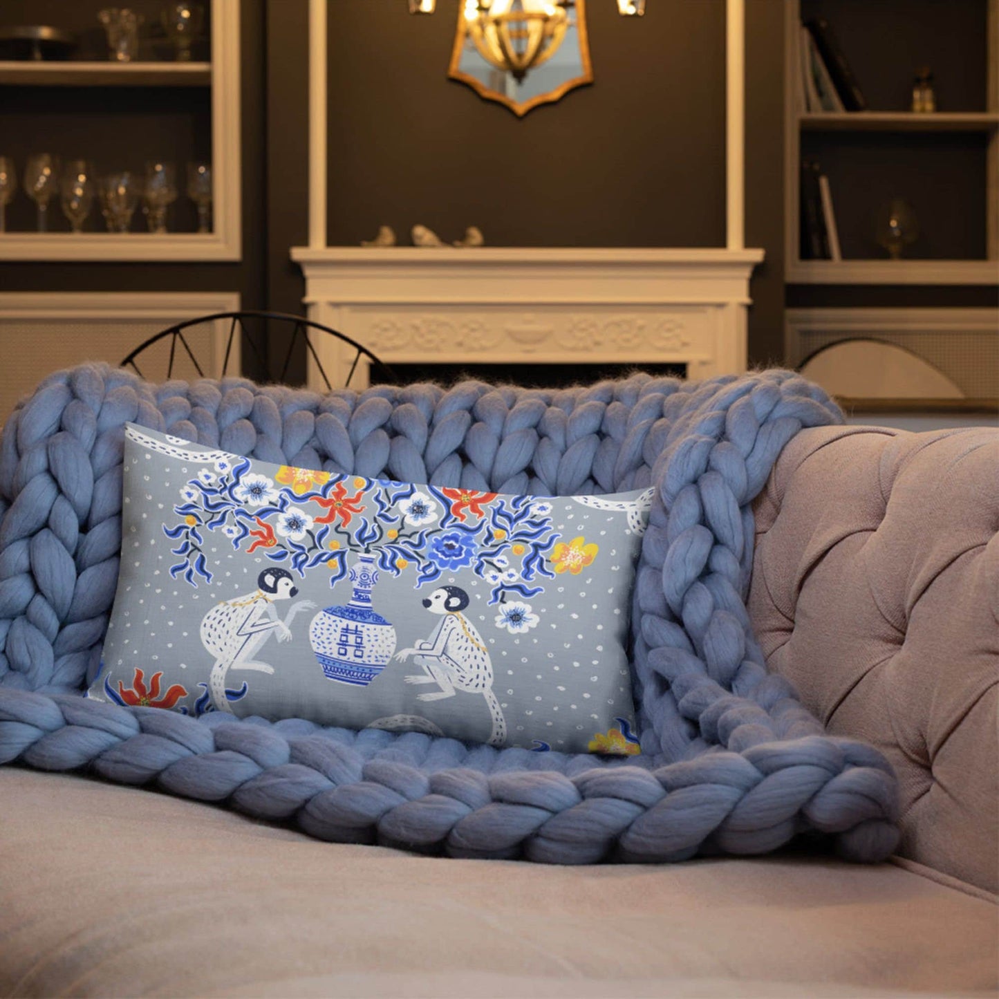 Grey chinoiserie monkey lumbar pillow . Oriental design on sofa with knit blanket.