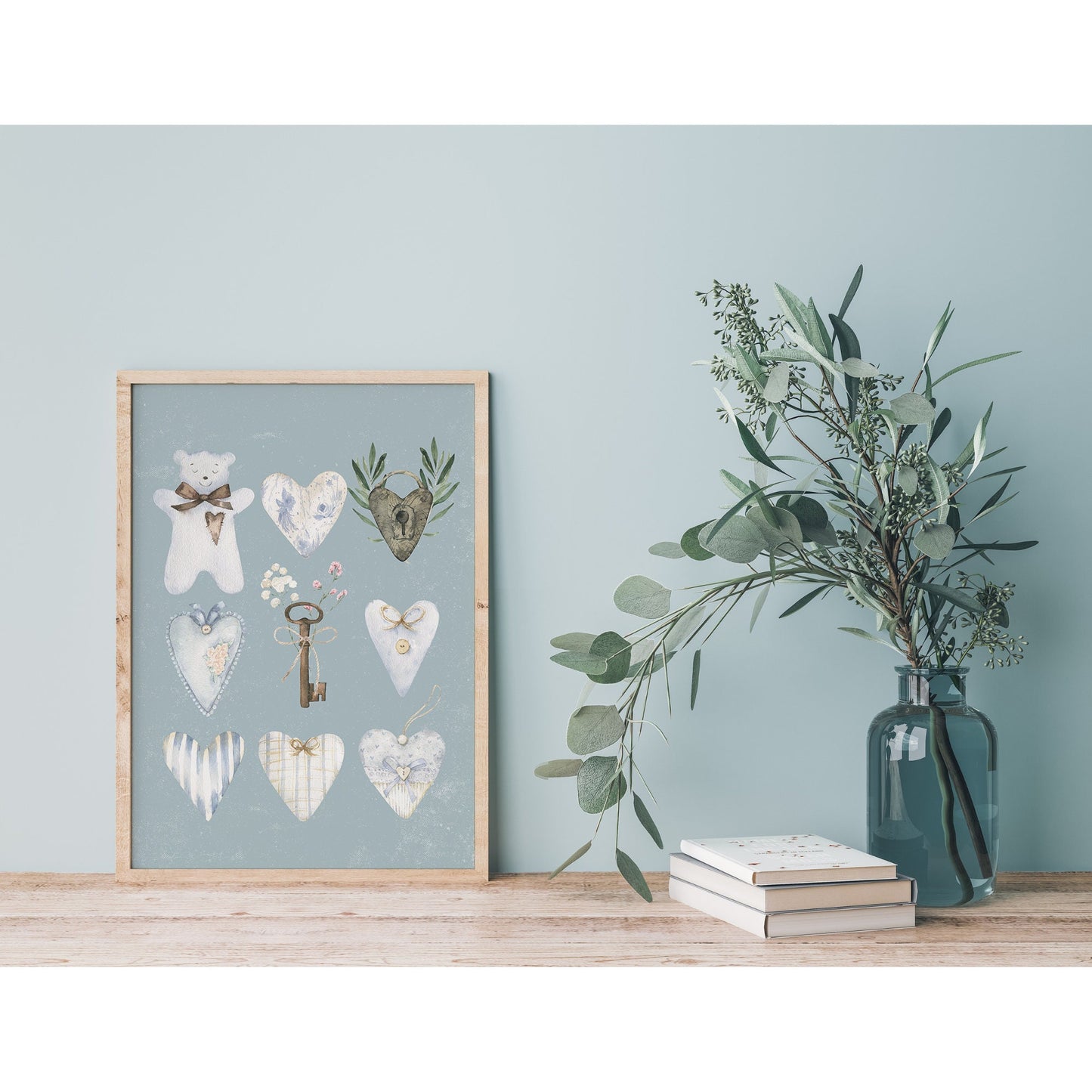 Watercolor Blue Hearts and Bear Painting leaning against blue wall next to leaves vase