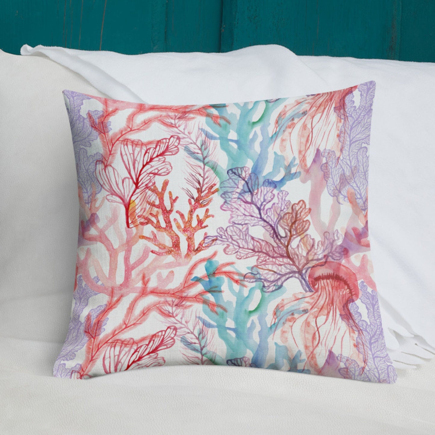 Coral reef pillow on bed with teal headboard. Ocean-themed decorative pillow with coral and jellyfish design.