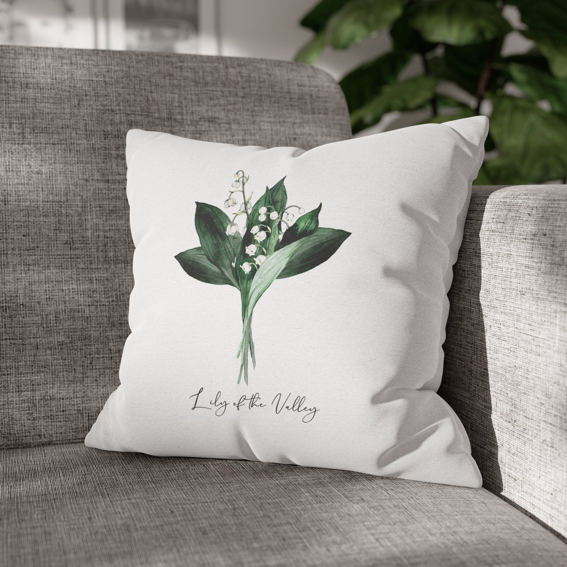 Lily of the valley throw pillow on grey armchair. Floral design decorative pillow with botanical illustration.