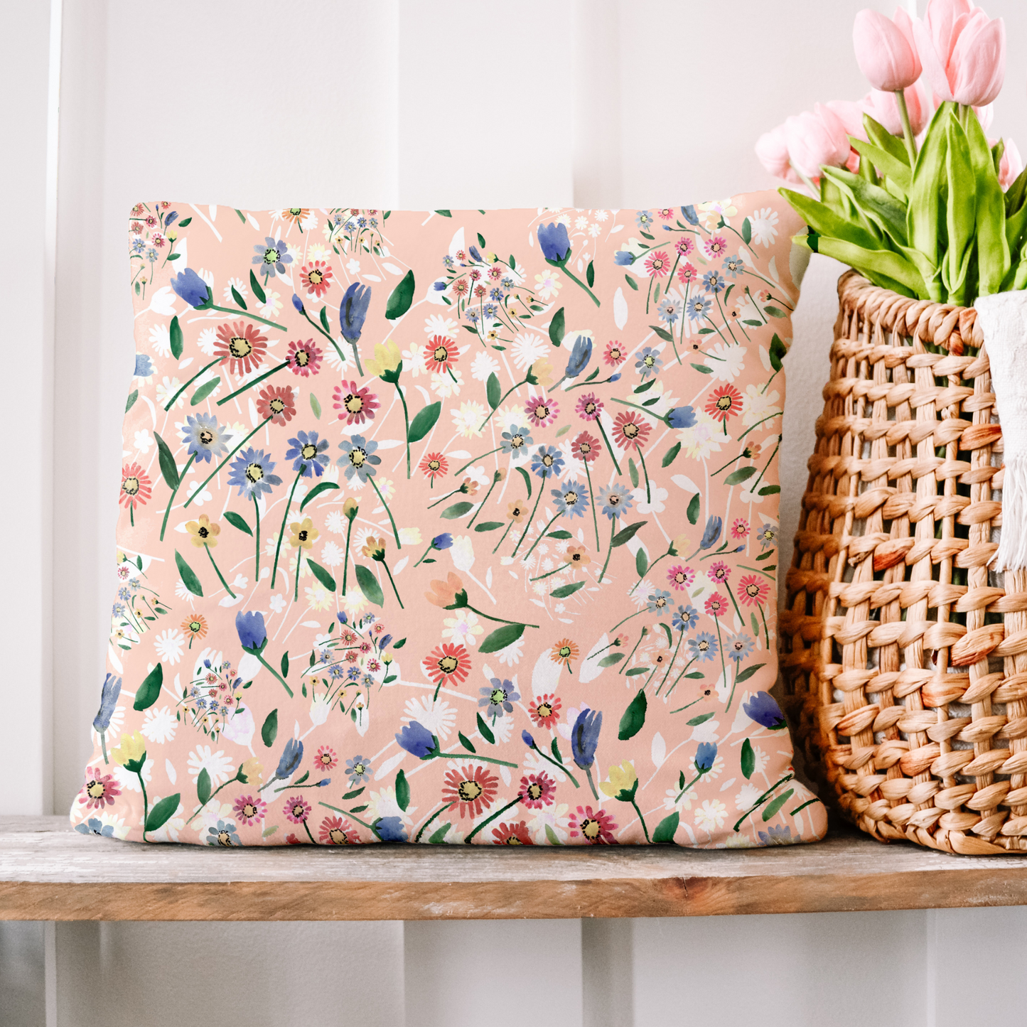 Pink Floral Spring PILLOW with vibrant wildflowers design on a shelf next to a basket of tulips.