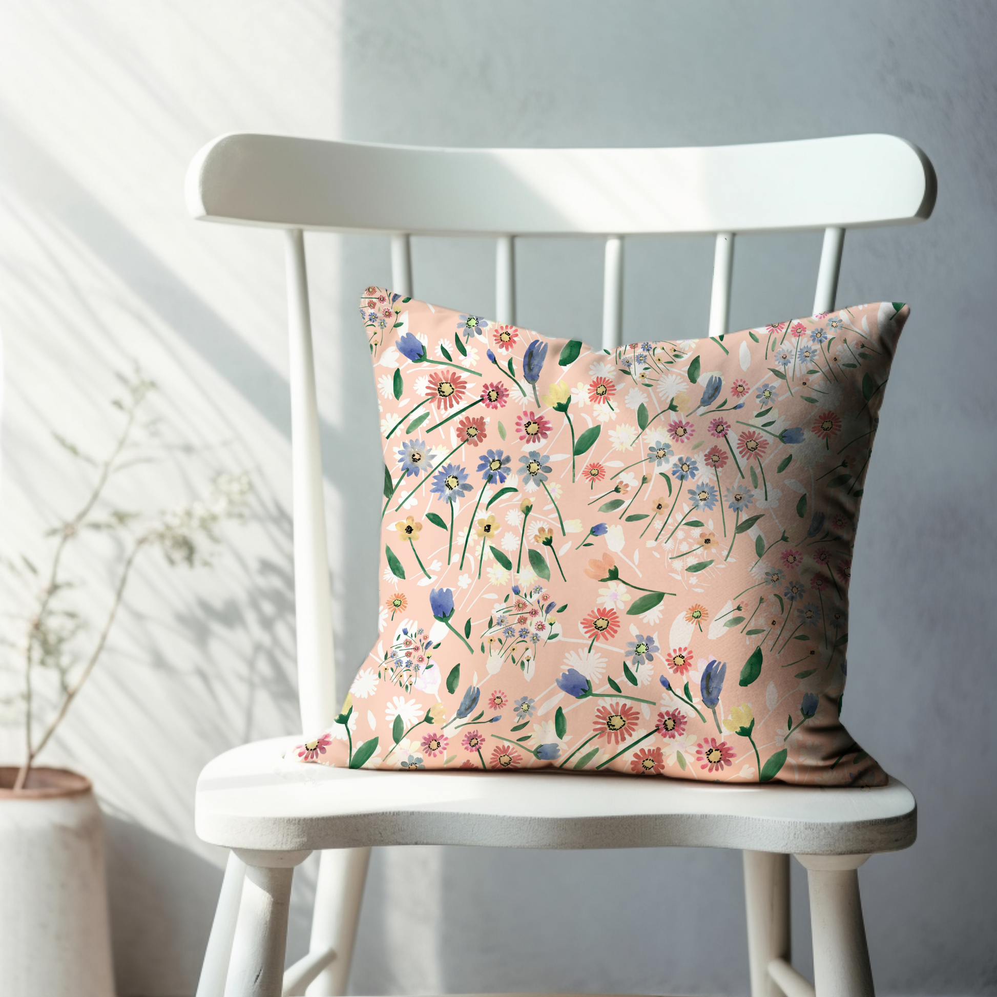 Pink Floral Spring PILLOW with wildflowers design displayed on a chair in a bright room.