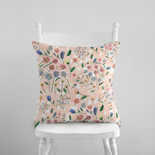 Pink Floral Spring PILLOW with wildflowers design on a soft pink background, displayed on a white chair.