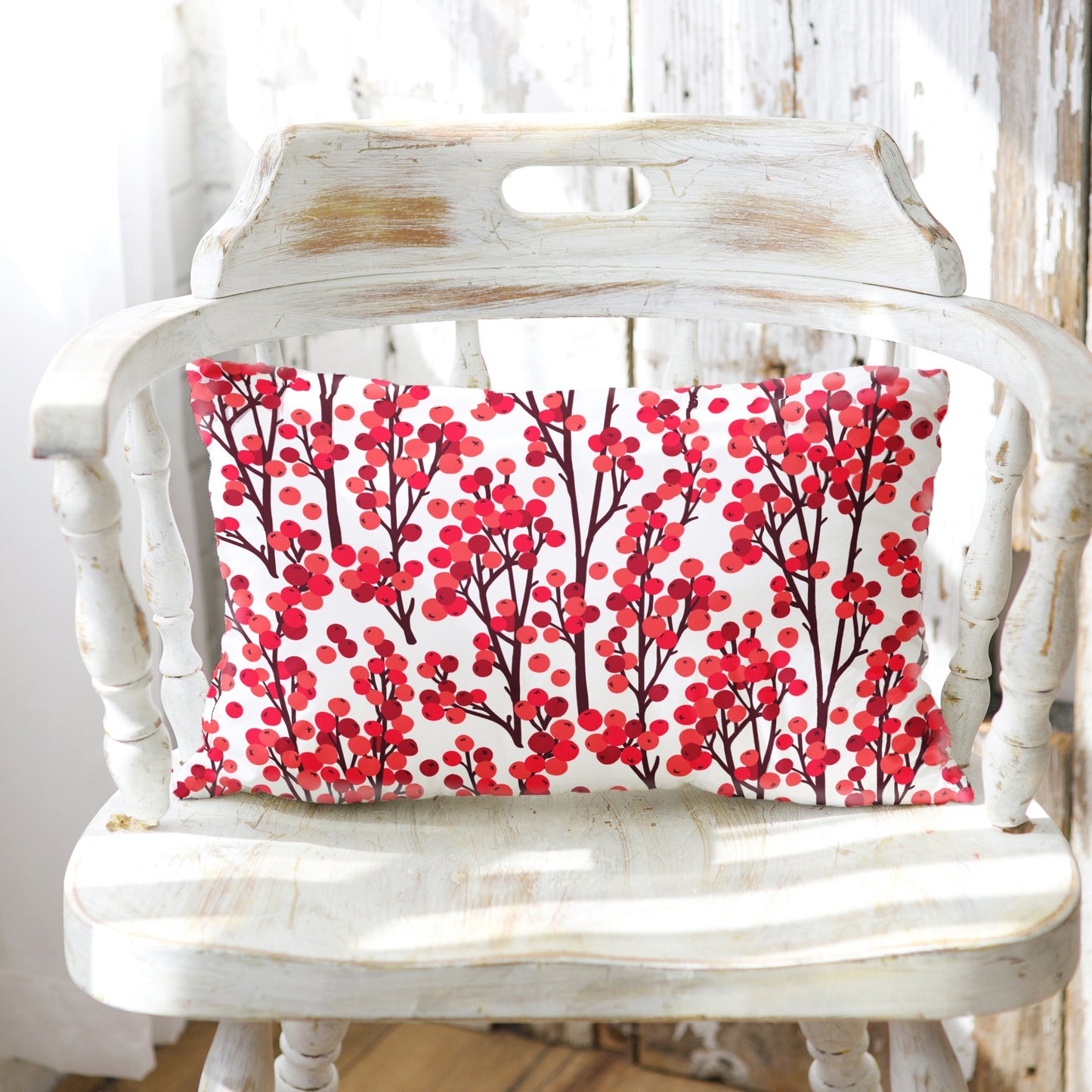 Red winter berry botanical lumbar pillow on distressed white wooden chair in sunlight