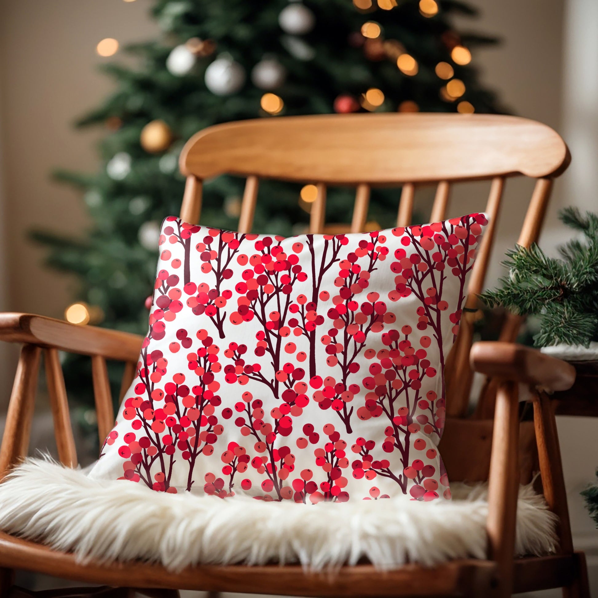 Red winter berry botanical pillow on wooden rocking chair with Christmas tree in background