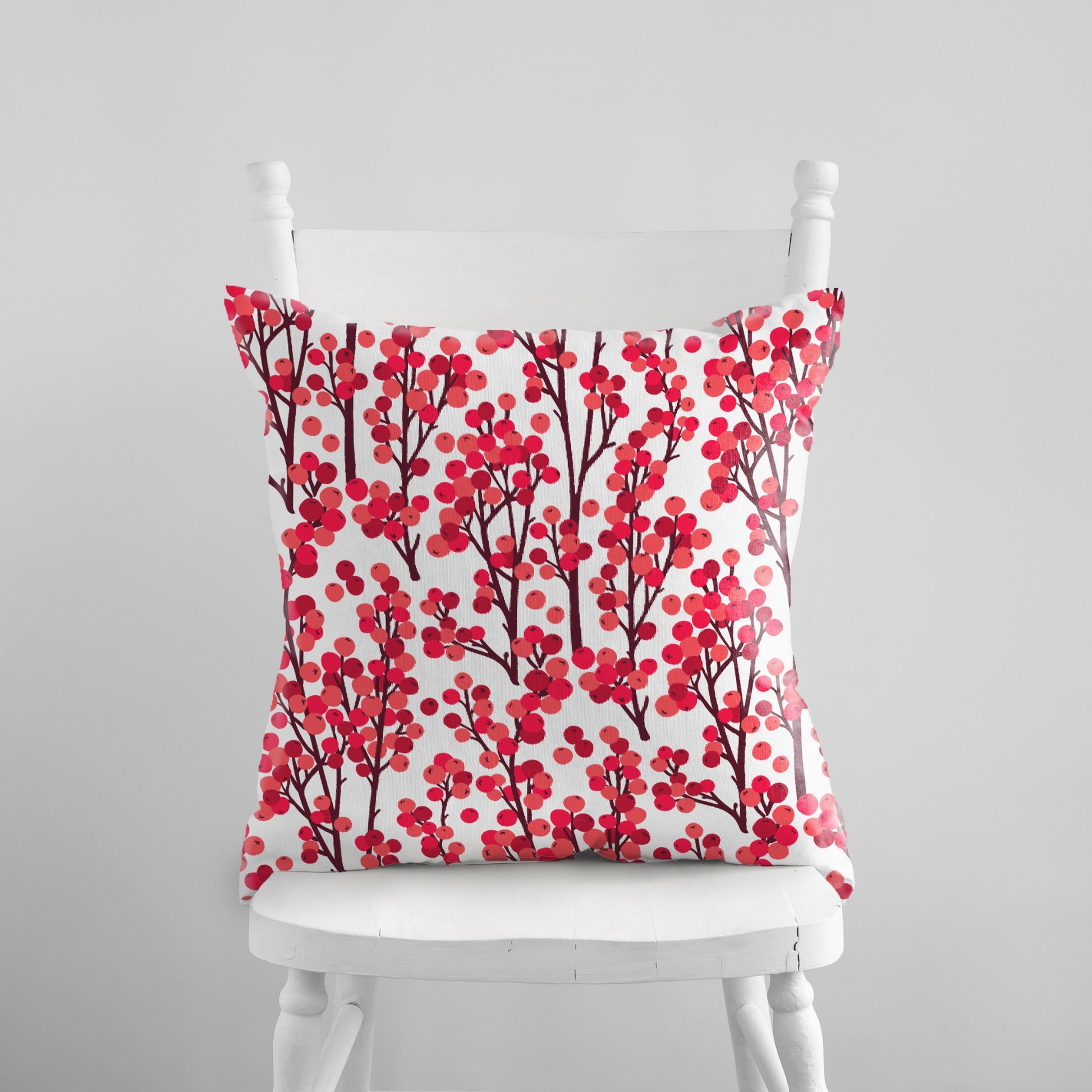 Red winter berry botanical pillow on white chair – festive nature-inspired seasonal decor