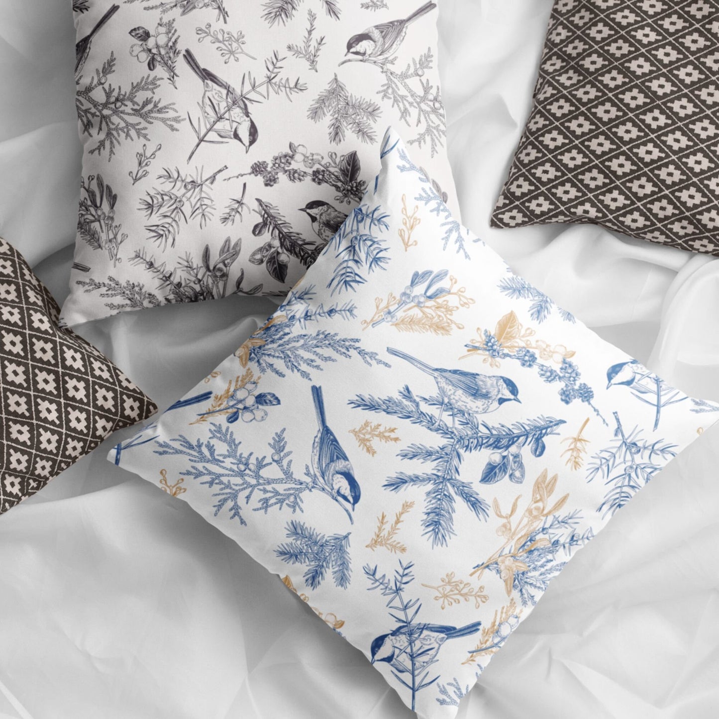 Vintage blue bird botanical winter pillow styled with neutral patterned cushions on white fabric