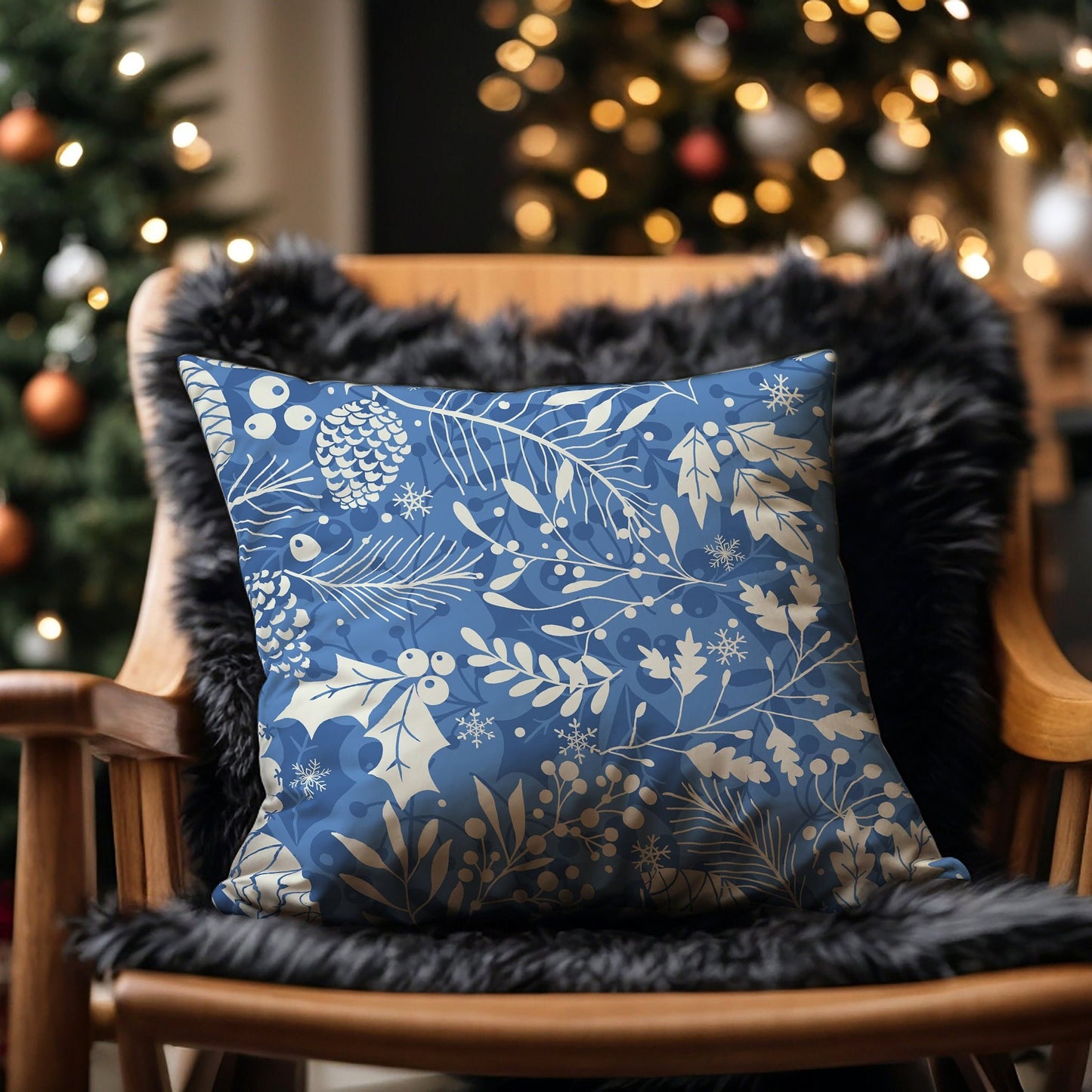 Light blue pillow with cream pinecones, leaves, and snowflakes on chair by Christmas tree