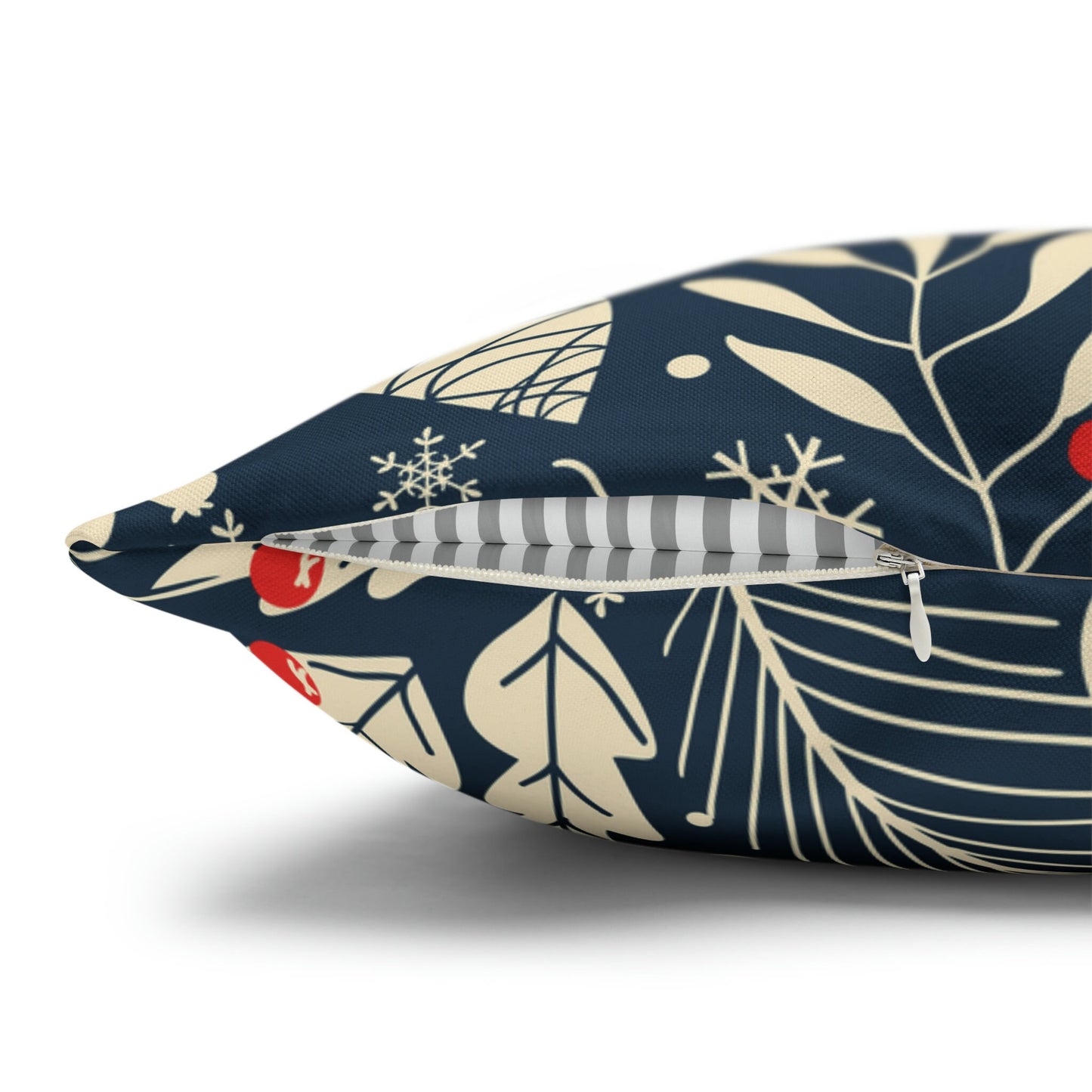 Close-up of navy winter botanical pillow with hidden zipper, cream leaves, and red berries